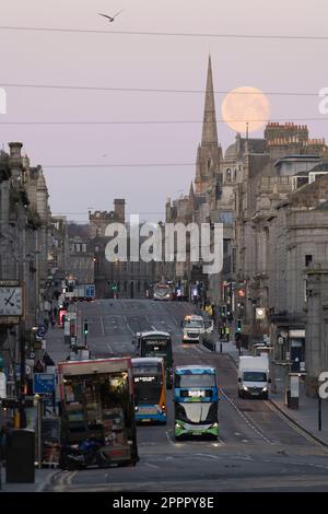 La Luna piena (Luna Rosa) che si trova dietro la guglia della chiesa di Gilcomston, vista lungo la lunghezza di Union Street nel centro di Aberdeen Foto Stock