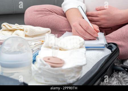 Donna incinta che scrive la lista delle cose per l'ospedale di maternità. Concetto di aspettarsi un bambino Foto Stock