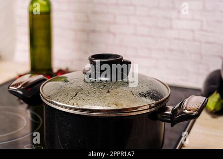 Acqua bollente in pentola di vetro trasparente sul piano cottura Foto stock  - Alamy