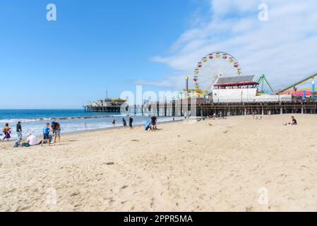 Persone che si godono una calda giornata autunnale sulla spiaggia di Santa Monica. Il Molo è sullo sfondo. Foto Stock