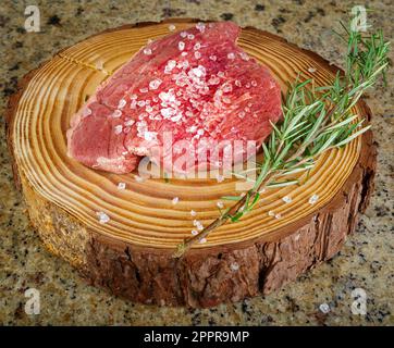 Bistecca di Picanha cruda su sfondo di legno in stile rustico con sale ed erbe aromatiche Foto Stock