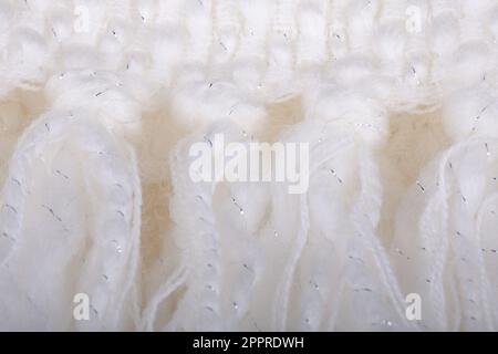 La frangia del primo piano su una morbida coperta a maglia è bianca croccante. Arredamento, design, decorazione, texture. Foto Stock