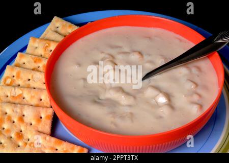 Un recipiente per la cottura a vapore di clam chowder con cracker isolate su nero Foto Stock