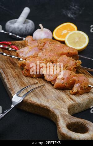 Spiedini con carne di tacchino marinata con ruche dolci e speziate su fondo scuro Foto Stock