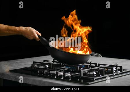 Processo di flambering degli ingredienti alimentari in una padella Foto Stock