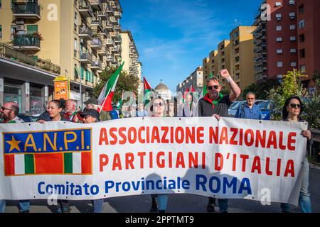 I manifestanti marciano dietro il banner ANPI recante l'iscrizione "Associazione nazionale dei partigiani del Comitato provinciale d'Italia di Roma" durante la manifestazione. Manifestazione sulle strade del quartiere Quadraro di Roma organizzata dall'ANPI (Associazione Nazionale dei Partigiani Italiani) e dal VII comune di Roma per commemorare il raduno del Quadraro. Il radunamento del Quadraro fu un'operazione militare nazista, effettuata il 17th aprile 1944, nella quale furono arrestate circa duemila persone, 683 delle quali furono deportate nei campi di concentramento tedeschi. Foto Stock