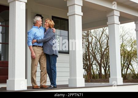 Theres nessun posto come la sede. una coppia matura felice in piedi sulla soglia della loro casa. Foto Stock