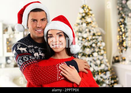 Felice coppia in cappelli Santa a casa. Festa di Natale Foto Stock