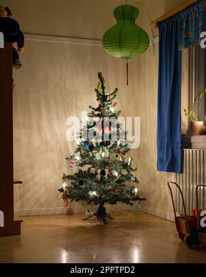 Albero di natale decorato con cura nell'angolo di una stanza Foto Stock