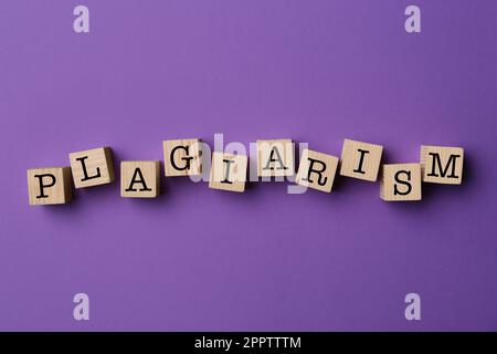 Plagio di parole fatto di cubi di legno su sfondo viola, vista dall'alto Foto Stock