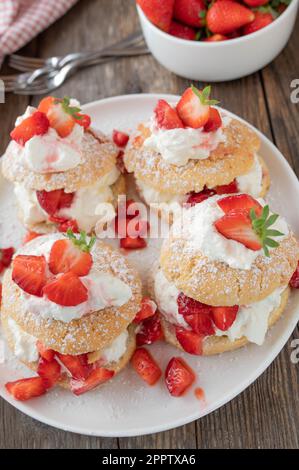 Dessert alle fragole con tradizionali tortine inglesi con panna montata alla vaniglia e fragole marinate su tavola di legno Foto Stock