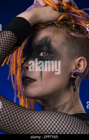 Fine arte ritratto di bellezza giovane donna con colorato senza pericolosi Dreadlocks acconciatura e spooky nero palco trucco dipinto sul viso. Foto da studio Foto Stock