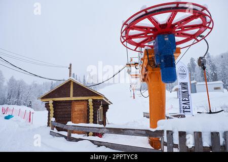 Iogach, Russia - 10 marzo 2018: Stazione sciistica invernale Teletsky Altai. Seggiovia Clasp sul monte e sullo sfondo della foresta sotto le nevicate. L'iscrizione Foto Stock