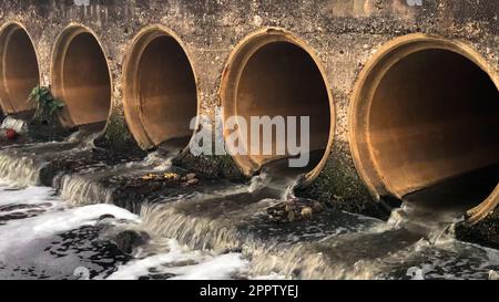 Acque reflue che confluiscono nel corpo fluviale e inquinano l'acqua e l'ambiente. Foto Stock