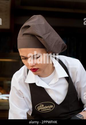 Majorca, Spagna -30, Marzo, 2023. Una cameriera femminile in uniforme serve un tavolo nel caffè SA Gelateria de Mallorca Foto Stock