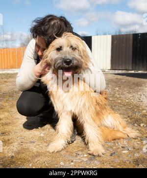 Donna accovacciata in un giardino che coccola un cane Foto Stock