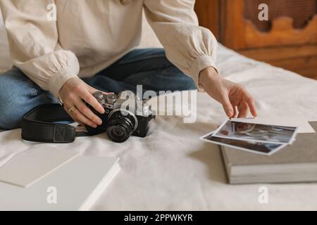 Primo piano di una donna elegante seduta sul letto con la sua macchina fotografica che guarda le foto Foto Stock