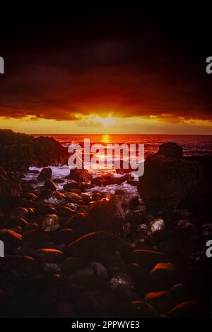 Alba sull'oceano Atlantico con rocce dalle sagome sulla riva dell'isola di Madeira in primo piano. Foto Stock