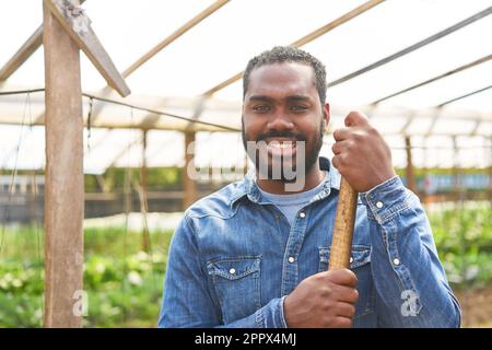 Ritratto di un contadino sorridente maschio che indossa una camicia in denim blu in serra Foto Stock