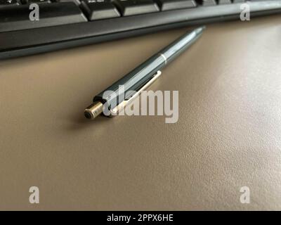 Penna a sfera verde automatica per scrivere sulla scrivania dell'ufficio con tastiera del computer. Lavoro aziendale. Foto Stock