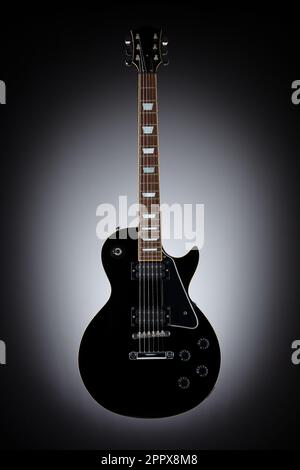 Chitarra nera isolata e fluttuante su sfondo grigio eclisse Foto Stock