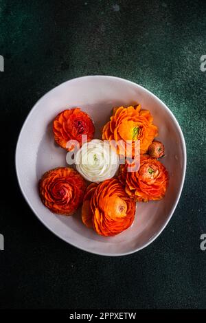 Vista dall'alto della decorazione d'interni con ciotola piena di testa di fiori Ranunculus su tavolo di cemento Foto Stock