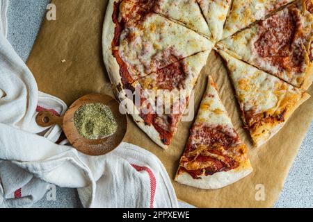 Pizza fatta in casa appena sfornata con erbe italiane e parmigiano sul tavolo Foto Stock