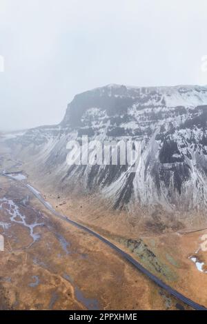 Veduta aerea della dorsale montuosa di Lomagnudur coperta di neve in una nuvolosa giornata invernale in Islanda Foto Stock