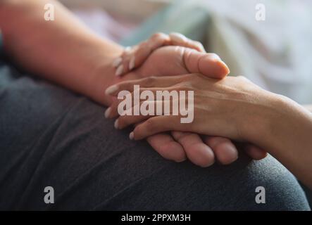 Figlia emotivamente sostenendo e confortando il padre anziano mentre tiene la mano Foto Stock