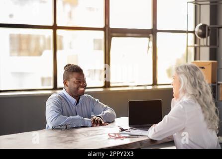 Uomo d'affari afro-americano che ha un lavoro Intervista con Businesswoman in ufficio Foto Stock