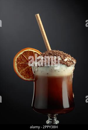Cocktail al cioccolato con panna montata cosparsa di gocce di cioccolato e guarnita con una fetta di arancia secca. Spazio di copia. Foto Stock