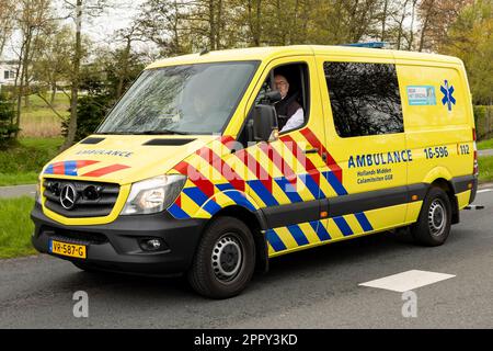 Noordwijk, PAESI BASSI - 22 aprile 2023: Guida lenta di un veicolo di ambulanza giallo olandese con numero di telefono di emergenza 112 Foto Stock