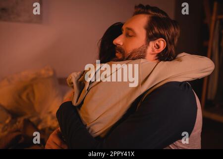 uomo attento abbracciando e calmando giù ragazza a casa in serata, immagine di scorta Foto Stock