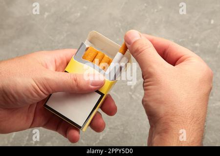 Mano dell'uomo che tiene la buccia esso dal pacchetto della sigaretta prepari fumare una sigaretta. Vista dall'alto. Foto Stock