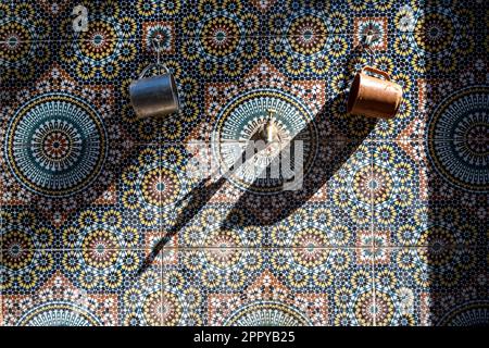 Due calici appesi sulle piastrelle di una fontana decorata. Foto Stock