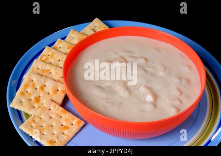 Un recipiente per la cottura a vapore di clam chowder con cracker isolate su nero Foto Stock