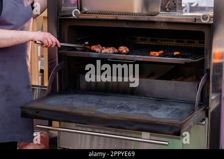 Chef che cucina bistecche di carne alla griglia al festival all'aperto Street food Foto Stock