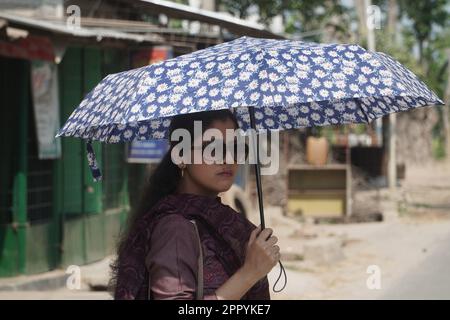 Naogaon, Bangladesh. 25th Apr, 2023. Una ragazza usa un ombrello per evitare il sole durante un'onda di calore vicino a Dhamoirhat del distretto di Naogaon. (Credit Image: © MD Mehedi Hasan/ZUMA Press Wire) SOLO PER USO EDITORIALE! Non per USO commerciale! Foto Stock