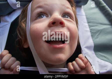 Un ragazzino guarda fuori dalla finestra della tenda, si diverte molto Foto Stock