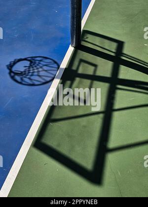 Un colpo verticale dell'ombra di un canestro da basket su un campo soleggiato Foto Stock