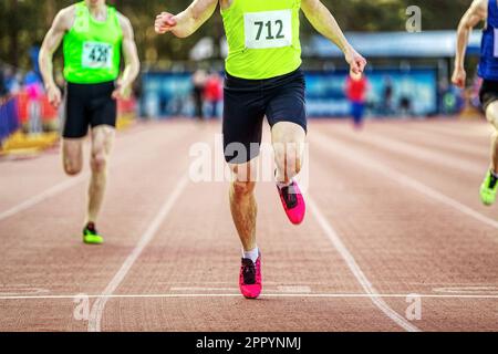 atleta maschile corridore attraversa il traguardo linea sprint corsa nei campionati di atletica, primo piano uomo sprinter vincitore della concorrenza Foto Stock