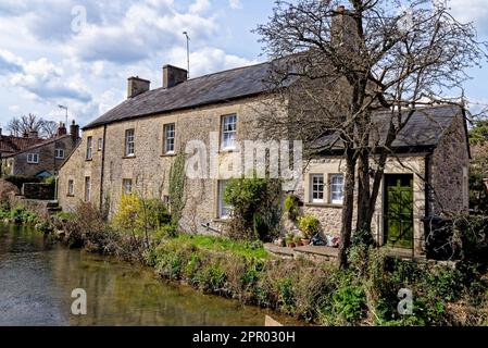 Graziosi cottage e il fiume Mells a Nunney. Villaggio di Nunney, Somerset, Inghilterra, Regno Unito - 8th aprile 2023 Foto Stock