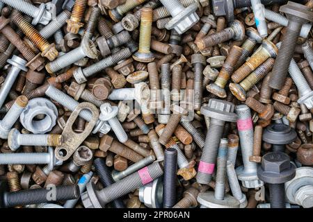 Sfondo con molti bulloni e dadi nuovi e usati di varie dimensioni e colori Foto Stock