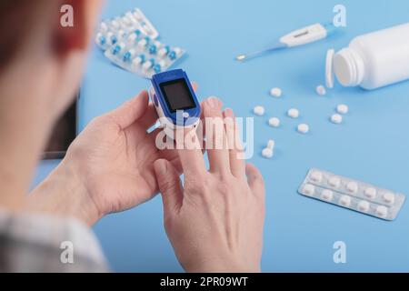 Donna che esegue l'autotest per i livelli di ossigeno nel sangue dal pulsossimetro Foto Stock