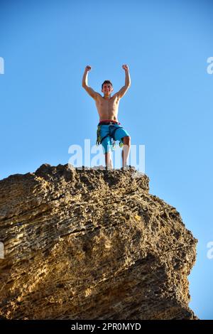 Arrampicatore estremo che alza le mani sulla cima della montagna. Concetto di successo Foto Stock