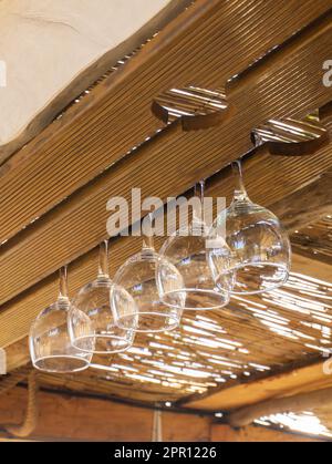 Bicchieri da vino appesi al sole su un bar in legno sulla spiaggia Foto Stock