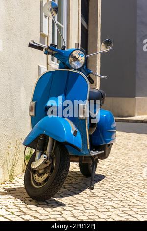 Ciclomotore blu brillante parcheggiato su una strada europea da vicino Foto Stock