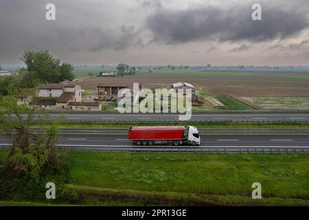 Autocarri e automobili da carico in autostrada A1 punto di vista aereo in pianura padana tra i campi rurali Foto Stock