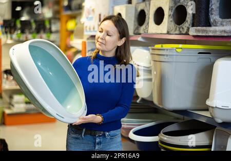 Donna gatto proprietario scelta vassoio di plastica lettiera in negozio di animali domestici Foto Stock