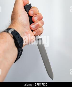 Mano maschio che tiene un coltello da sega Foto Stock